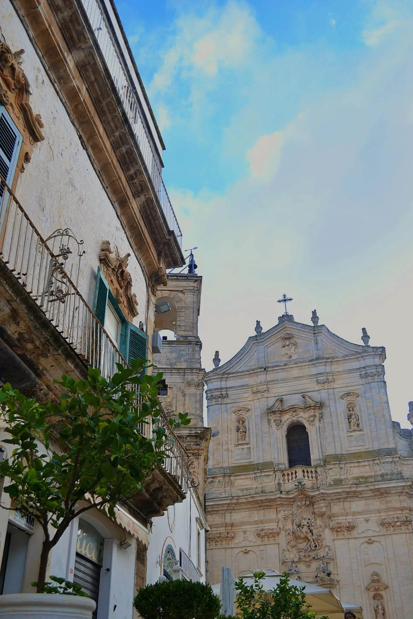 La facciata barocca della Basilica di San Martino a Martina Franca vista dalla via, tra i balconi in ferro battuto dei palazzi del centro storico