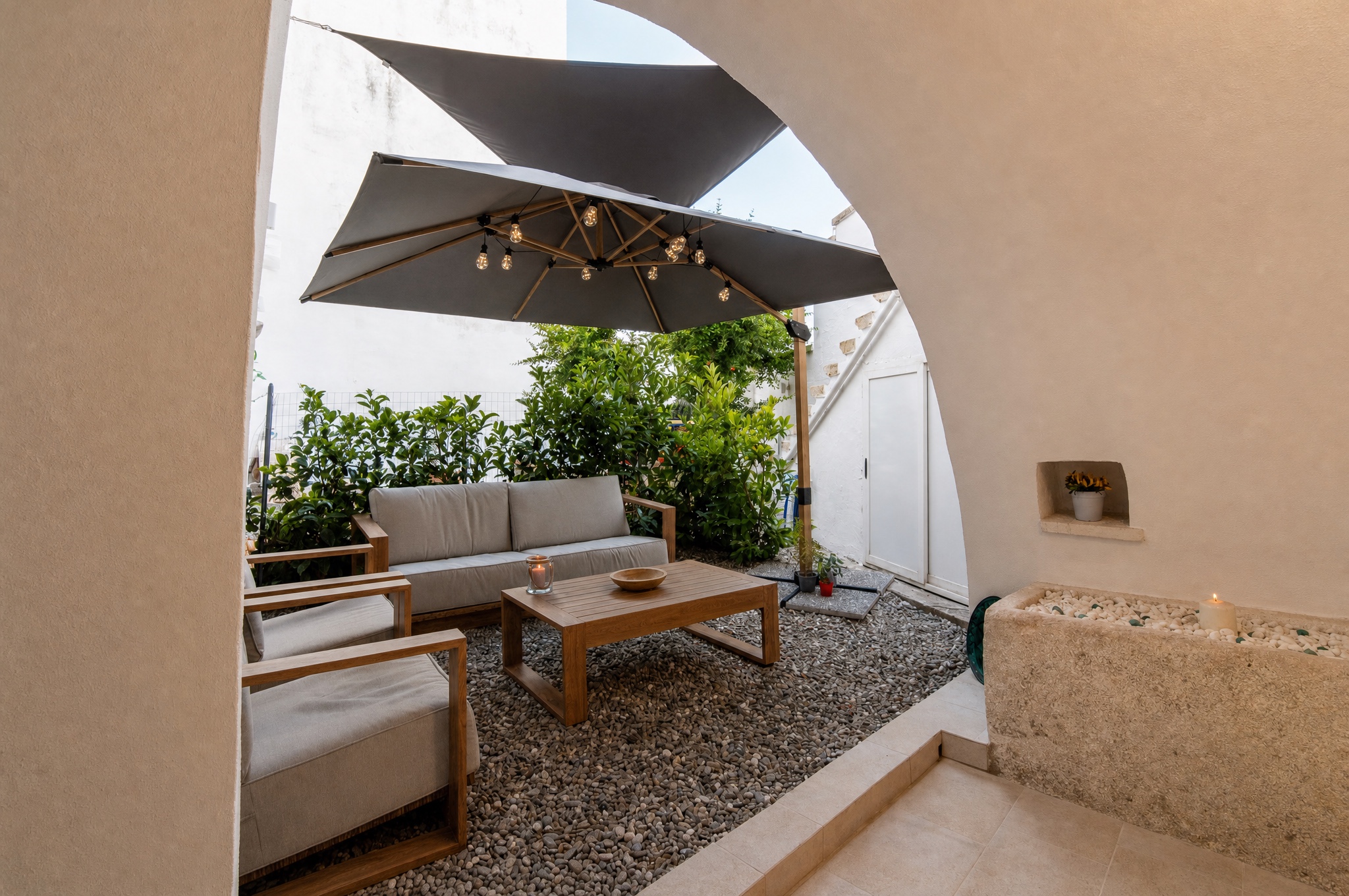 La corte privata con divani in teak, ombrellone e vegetazione mediterranea